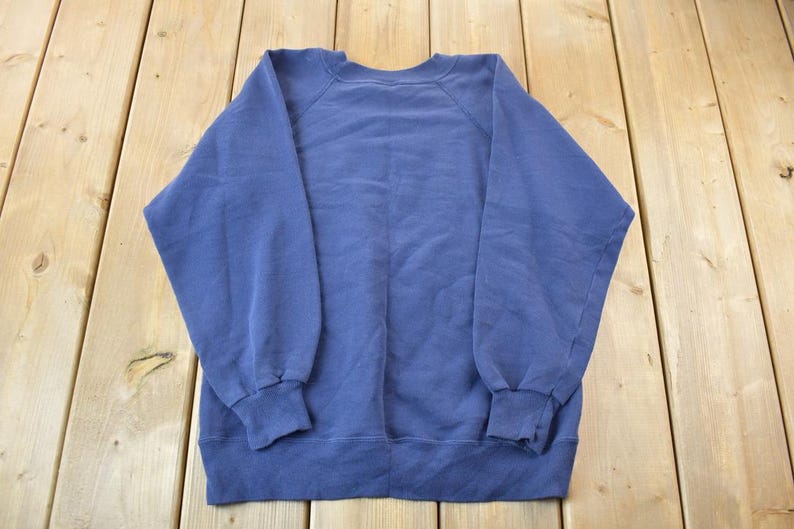 May include: A solid blue sweatshirt with a crew neck and long sleeves.