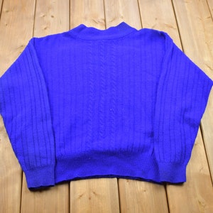 Peut inclure: Un pull bleu vif à manches longues avec une texture côtelée.