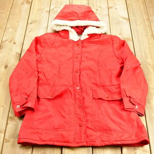 May include: A red hooded winter jacket with a white faux fur lining around the hood. The jacket has a button closure and two front pockets.