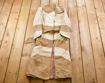 May include: A long, striped, brown and white leather coat with a collar and a belt.