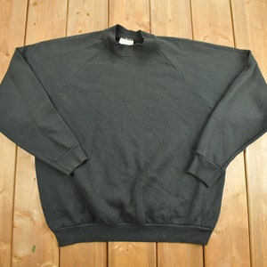 Könnte beinhalten: Ein schwarzer Langarm-Pullover mit Stehkragen.