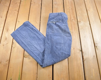 May include: A pair of blue corduroy pants folded in half on a wooden surface.
