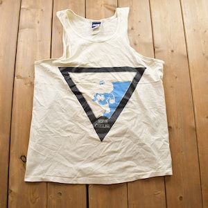 May include: White tank top with a black triangle graphic featuring a blue outline of the state of North Carolina and the text "North Carolina".