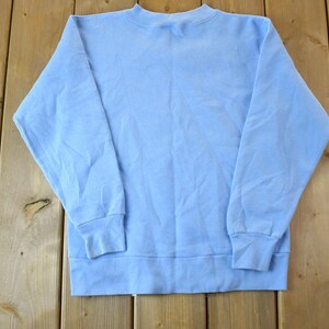 May include: A light blue sweatshirt with long sleeves and a crew neck.