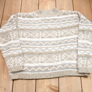 May include: A beige and white patterned sweater with a high neck.