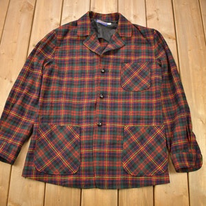 May include: A red, green and black plaid button-up shirt with two large pockets on the front.