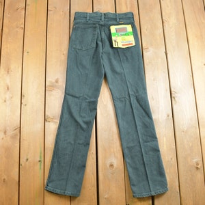 May include: A pair of dark blue denim jeans with a Wrangler label on the back pocket.