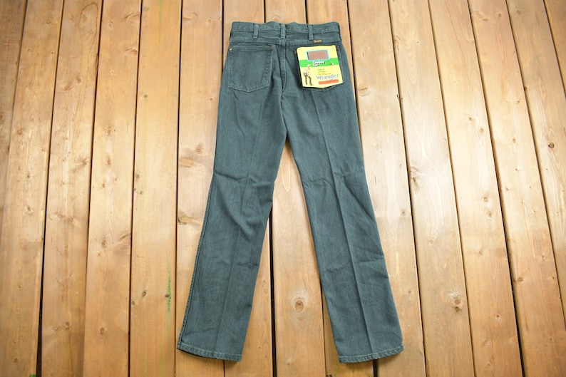 May include: A pair of dark blue denim jeans with a Wrangler label on the back pocket.