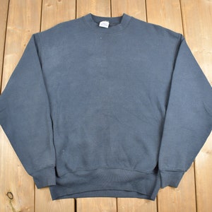 Könnte beinhalten: Ein dunkelblauer Pullover mit langen Ärmeln und einem Rundhalsausschnitt.