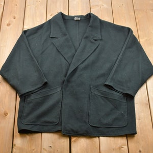 May include: A black, long-sleeved jacket with a collar and two pockets. The jacket is made of a soft, comfortable fabric.