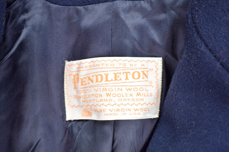 Pu&ograve; includere: Un'etichetta bianca con il testo "WARRANTED TO BE A PENDLETON" in lettere arancioni. L'etichetta riporta anche "100% VIRGIN WOOL PENDLETON WOOLEN MILLS PORTLAND, OREGON PURE VIRGIN WOOL MADE IN USA".