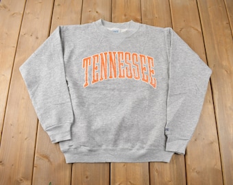 May include: Grey sweatshirt with an orange "TENNESSEE" arch design.