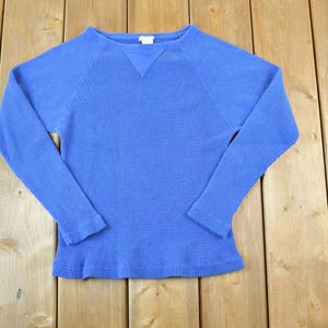 May include: A long-sleeved, blue waffle knit shirt with a crew neck.