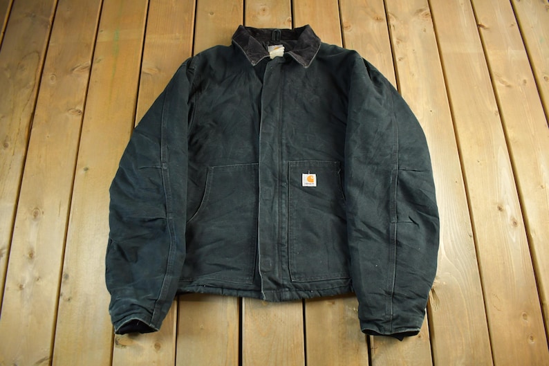 Puede incluir: Chaqueta de trabajo verde oscuro con cuello de pana y cierre de botones. La chaqueta tiene dos bolsillos delanteros grandes y un peque&ntilde;o parche cuadrado con el logo. La chaqueta est&aacute; hecha de un material duradero.