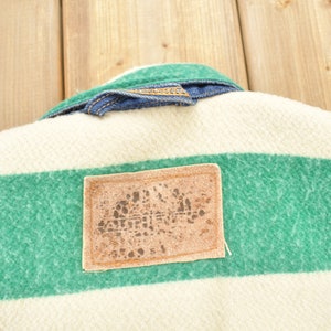 May include: A white and green striped fabric with a brown leather patch. The patch has a logo with the word "ARCTIC" printed on it.
