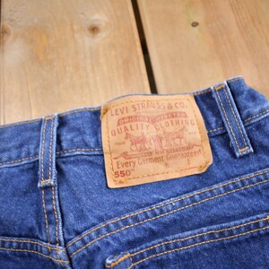 May include: Blue denim jeans with a brown leather patch that reads "Levi Strauss & Co. Original  Riveted Quality Clothing  Every Garment Guaranteed 550&trade;"