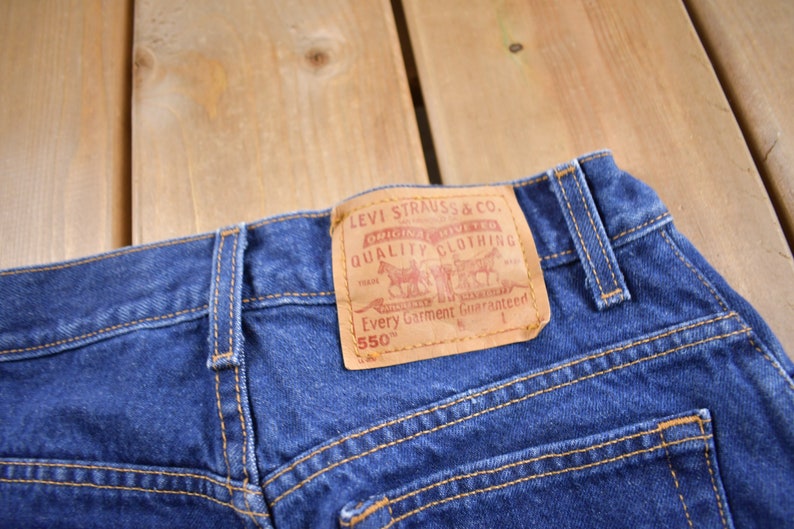 May include: Blue denim jeans with a brown leather patch that reads "Levi Strauss & Co. Original  Riveted Quality Clothing  Every Garment Guaranteed 550&trade;"