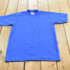 May include: A solid blue short-sleeve t-shirt with a crew neckline. The garment features a plain, unpatterned design in a vibrant shade of blue, constructed with standard stitching along the sleeves and hem, and includes a small white brand label.