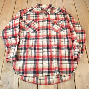 May include: A red, black, and white plaid flannel shirt with long sleeves and a button-down front.