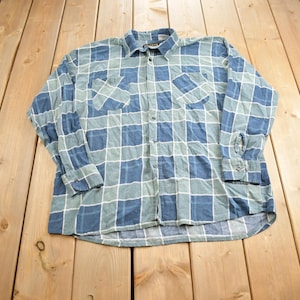 May include: A blue and green plaid long-sleeved button-up shirt with two chest pockets.