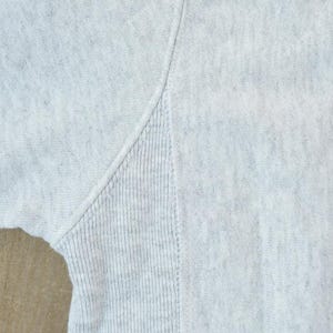Puede incluir: Primer plano de una sudadera gris con textura acanalada. La tela es suave y c&oacute;moda.