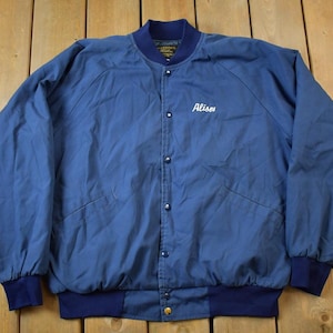 May include: A blue bomber jacket with a white embroidered name "Alison" on the front. The jacket has a snap closure and a ribbed collar, cuffs, and waistband.