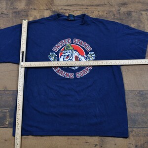 May include: A navy blue t-shirt with a graphic of a cartoon bulldog wearing a military hat. The graphic is surrounded by the text "United States Marine Corps".