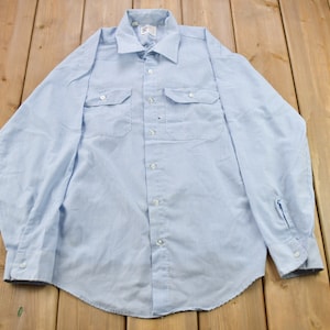 May include: A light blue striped long-sleeve shirt with two chest pockets and a button-down collar.