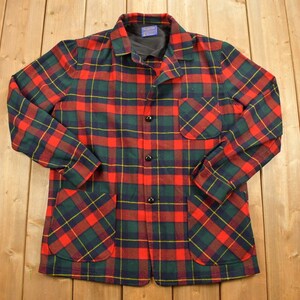 May include: A red, green and yellow plaid flannel shirt with two large pockets. The shirt has a button-up front and long sleeves.