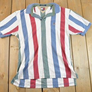 May include: A striped polo shirt with red, blue and green stripes. The shirt has a collar and a button placket. The shirt is made from a soft, comfortable fabric.
