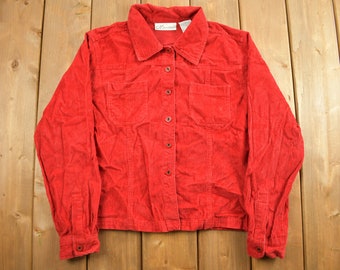 Puede incluir: Una camisa de pana roja con botones, mangas largas y dos bolsillos en el pecho.