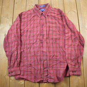 May include: A long-sleeved plaid shirt in red and green. The shirt has a button-down collar and a button-up front.