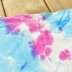 May include: A tie-dye fabric with blue, pink, and purple swirls. The fabric is white in some areas.