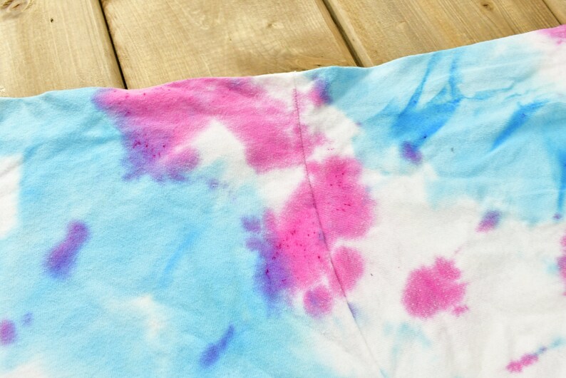 May include: A tie-dye fabric with blue, pink, and purple swirls. The fabric is white in some areas.
