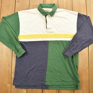 May include: A long-sleeved rugby shirt with a color block design. The shirt is green, white, yellow, and blue.