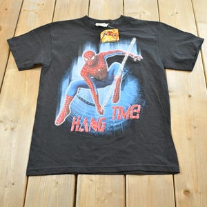 May include: Black t-shirt with a Spider-Man graphic, showing the superhero in a dynamic pose with the words "HANG TIME!" in red. The character is in his red and blue suit against a blue backdrop. A tag is attached to the shirt.