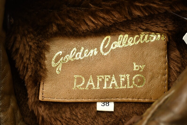 May include: A brown leather jacket with a fur collar. The label reads "Golden Collection by Raffaello" and has a size tag that says "38".