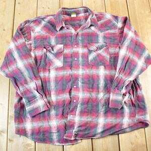 Puede incluir: Una camisa de cuadros de manga larga en tonos rojos, blancos y turquesas. La camisa tiene dos bolsillos en el pecho y una botonadura frontal. La tela tiene un aspecto suave y desgastado, lo que sugiere que es vintage.