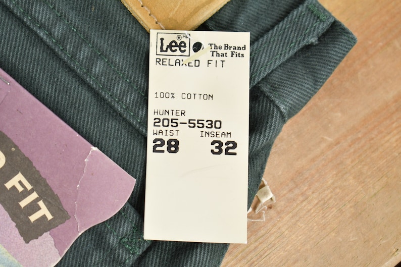 Może przedstawiać: Biała metka z czarnym tekstem, na kt&oacute;rej widnieje napis "Lee The Brand That Fits Relaxed Fit 100% Bawełna Hunter 205-5530 Talia 28 Długość nogawki wewnętrzna 32"