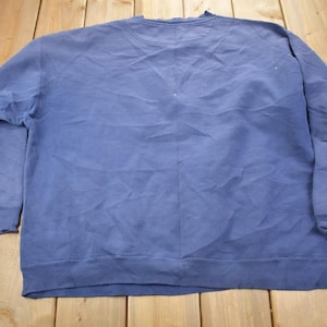 May include: A plain, blue sweatshirt with long sleeves and a crew neck. The sweatshirt is made of a soft, comfortable fabric.