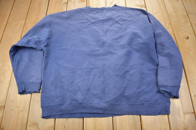 May include: A plain, blue sweatshirt with long sleeves and a crew neck. The sweatshirt is made of a soft, comfortable fabric.