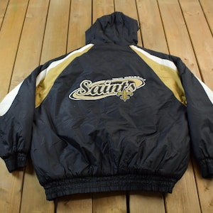 May include: Black and gold hooded jacket with the New Orleans Saints logo on the back. The jacket has white and gold stripes on the sleeves.