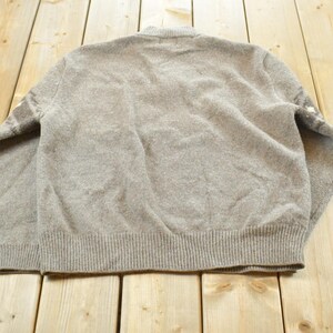 Peut inclure: Un pull &agrave; manches longues marron clair avec un ourlet et des poignets c&ocirc;tel&eacute;s. Le dos du pull est visible, montrant la texture du tissu tricot&eacute;. Le pull a un col rond et un design simple et classique.