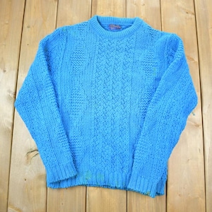 May include: A light blue knitted sweater with a cable knit pattern.