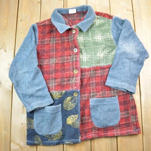 Puede incluir: Una chaqueta de forro polar de patchwork azul, rojo y verde con cierre de botones y dos bolsillos.