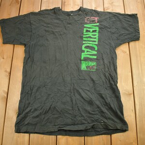 May include: A black t-shirt with a green vertical graphic that reads "GET VERTICAL MOUNTAIN KREW".