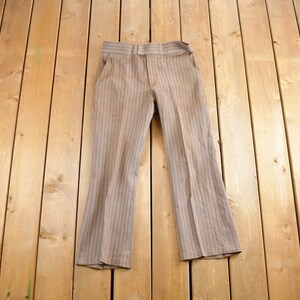 Puede incluir: Pantalón de pierna ancha a rayas marrones y blancas.
