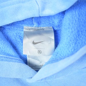 May include: A light blue hooded sweatshirt with a white tag that says "Nike" and "XL" on it.