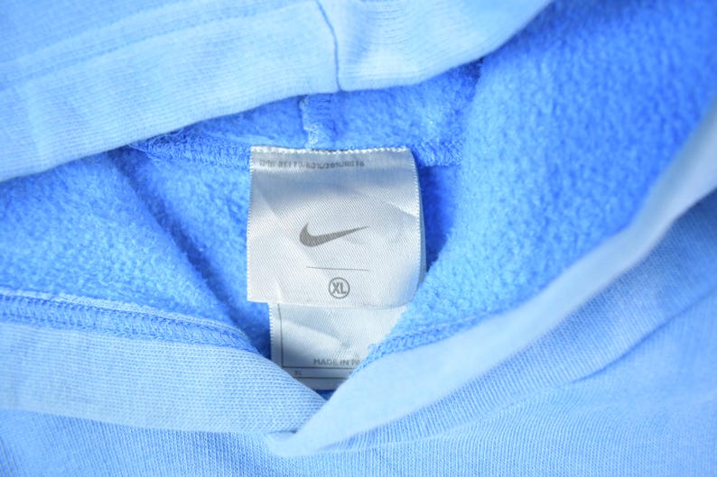 May include: A light blue hooded sweatshirt with a white tag that says "Nike" and "XL" on it.