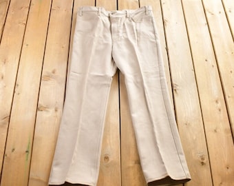 May include: A pair of light beige trousers with a straight leg fit. The trousers are made of a soft, comfortable fabric and have a classic style.
